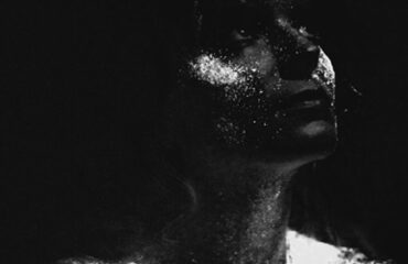 Woman pondering with UV paint splattered on face